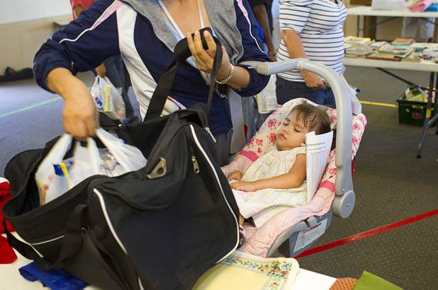 A woman holds he 1-year-old daughter as she picks up a bag of food at Sunrise Baptist Church, 1780 Betty Lane, Thursday, Aug. 23, 2012.