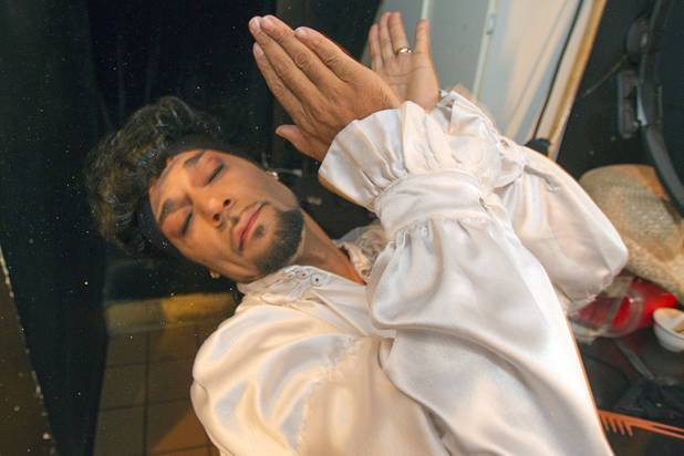 Prince impersonator Jason Tenner applies glitter to his face as ...
