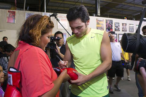 WBC middleweight champion Julio Cesar Chavez Jr., son of boxing legend Julio Cesar Chavez, signs a glove for boxing fan Diana Lopez at Top Rank Gym Thursday, Aug. 30, 2012, Chavez will defend his title against Sergio Martinez of Argentina at the Thomas & Mack Center Sept. 15.