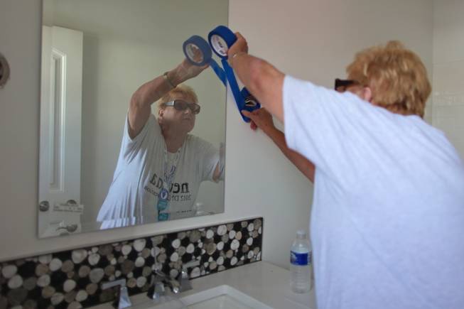 Dorie Guy, alternate delegate and chairwoman of the Washoe County Democratic Party, puts painter’s tape around an electrical socket in the bathroom of a modular home.