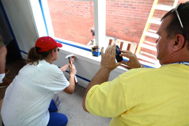Linda Cavazos, a Nevada delegate and an Organizing for America volunteer, hammers a nail into a window frame while Clark County Democratic Party chairman Chris Miller snaps a picture on his phone.

