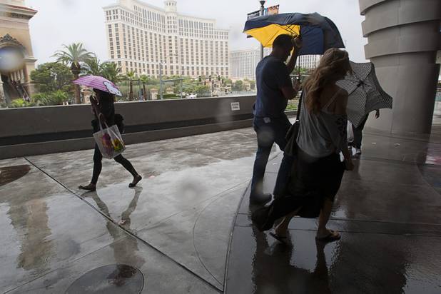 Tourists cope with heavy rainfall in front of Planet Hollywood during a rainstorm Tuesday, Sept. 11, 2012.