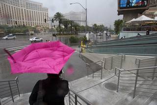Wind turns a woman's umbrella inside out in front of Planet Hollywood during a rainstorm Tuesday, Sept. 11, 2012.