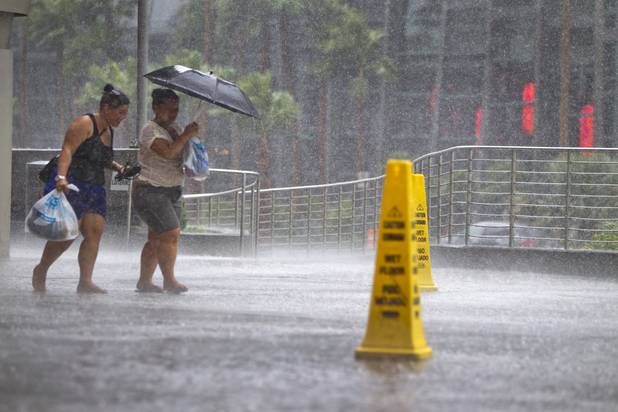 A pair of women make their way through heavy rain front of Planet Hollywood during a rainstorm Tuesday, Sept. 11, 2012.