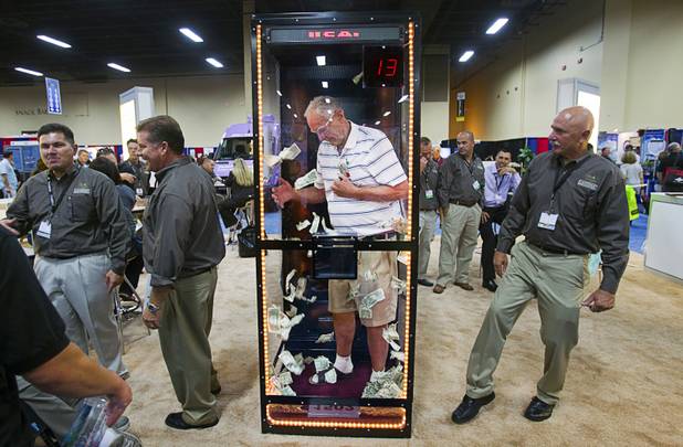 Gene De Boer, owner of All Mountain Feed and Supply in Big Bear, Calif., grabs money in a cash booth at the Canidae all natural pet food company during SuperZoo, a trade show for the pet industry, at the Mandalay Bay Convention Center Tuesday, Sept. 11, 2012. The cash booth was a reward to retailers that sold a lot of product, De Boer said.