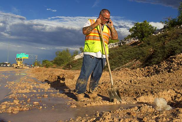 A Nevada Department of Transportation worker tries to find a cut-off to an irrigation pipe near the I-215 eastbound off-ramp to the airport connector Tuesday, Sept. 11, 2012. Run off from heavy rains filled the roadway with mud and debris.