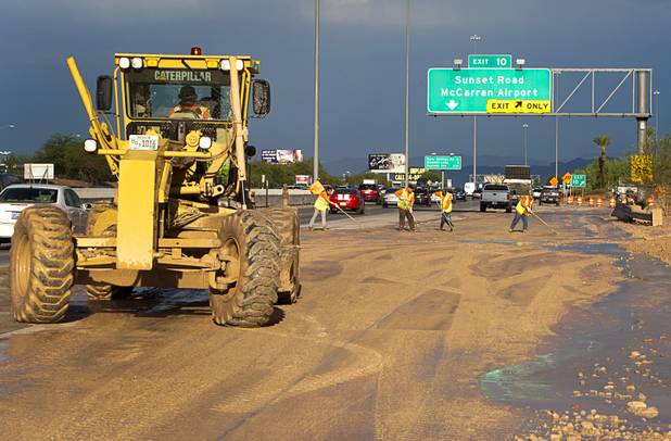 A Nevada Department of Transportation road crew works to clear the roadway at the I-215 eastbound off-ramp to the airport connector Tuesday, Sept. 11, 2012. Run off from heavy rains filled the roadway with mud and debris.