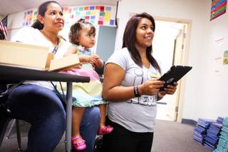 Eighth-grader Monique Aguilar, from right, 13, learns to use her new iPad accompanied by her 16-month-old sister Yuritzi Cepeda and mother Blanca DeLeon at Ed Von Tobel Middle School in Las Vegas on Thursday, Sept. 19, 2012. The Clark County School District's Engage, Empower, Explore (E3) program provided iPads for all students and teachers at five Title I middle schools.