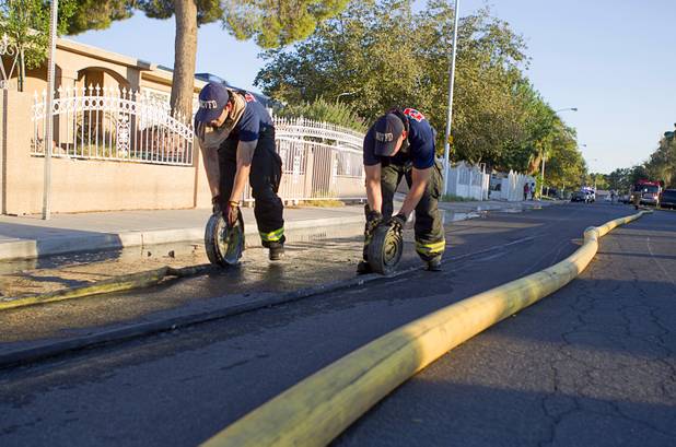 North Las Vegas firefighters roll up hoses after fighting a fire that damaged six homes in a neighborhood near Washington Avenue and Pecos Road Sunday, Sept. 23, 2012. Firefighters from the City of Las Vegas Fire Department, Clark County Fire Department, North Las Vegas Fire Department responded to fight the fires. Four people suffered injuries. One cat was killed.