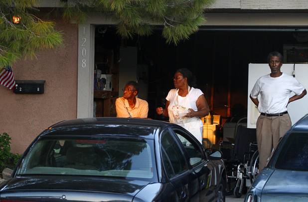 Neighbors watch from their garage as fighters put out a fire that damaged six homes in a neighborhood near Washington Avenue and Pecos Road Sunday, Sept. 23, 2012. Firefighters from the City of Las Vegas Fire Department, Clark County Fire Department, North Las Vegas Fire Department responded to fight the fires. Four people suffered injuries. One cat was killed.