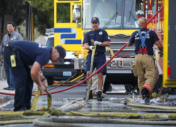 Firefighters break down hoses after fighting a fire that damaged six homes in a neighborhood near Washington Avenue and Pecos Road Sunday, Sept. 23, 2012. Firefighters from the City of Las Vegas Fire Department, Clark County Fire Department, North Las Vegas Fire Department responded to fight the fires. Four people suffered injuries. One cat was killed.