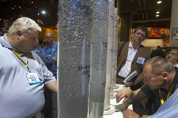 Show attendees look over crushed ore at the Sandvik booth during the MINExpo International 2012 trade show at the Las Vegas Convention Center Monday, Sept. 24, 2012. The company unveiled a new energy-efficient crusher/grinder at the show.
