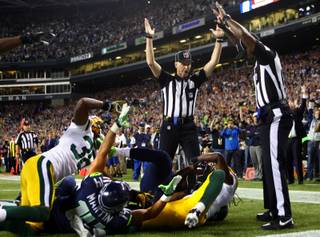 Officials signal after Seattle Seahawks wide receiver Golden Tate pulled in a last-second pass for a touchdown from quarterback Russell Wilson to defeat the Green Bay Packers 14-12 in an NFL football game, Monday, Sept. 24, 2012, in Seattle. The touchdown call stood after review. 