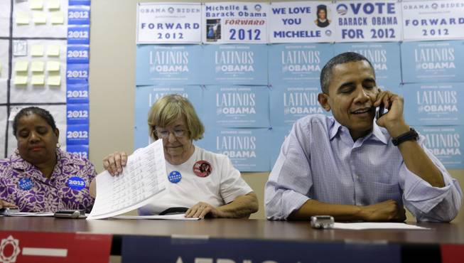 President Barack Obama, right, sits down with volunteers to make phone calls to supporters during a visit to a local campaign office, Monday, Oct. 1, 2012 in Henderson, Nev. 