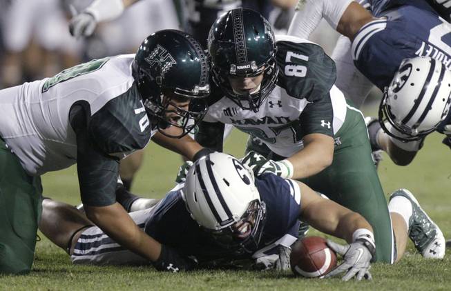 A Brigham Young player dives onto a fumble as Hawaii offensive linesman Frank Loyd Jr. (70) and tight end Ryan Hall (87) watch during the third quarter of an NCAA college football game Friday, Sept. 28, 2012, in Provo, Utah. 