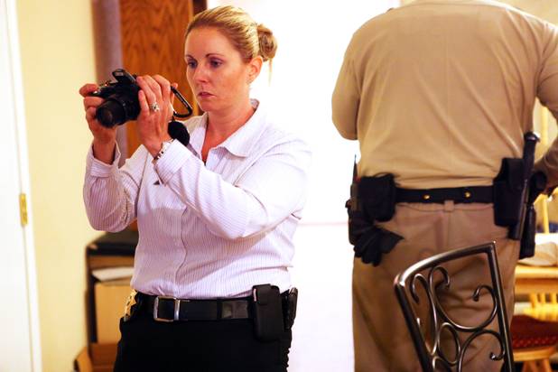 Coroner investigator Lara Davies takes photos of a scene with a dead body in Las Vegas.