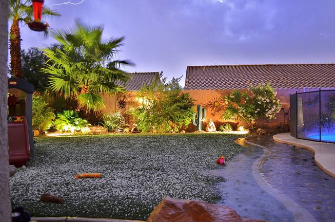 A backyard in Henderson is illuminated by lightning amid a thunderstorm late Thursday, Oct. 11, 2012. Hail was reported in various parts of Henderson; its accumulation is seen on the grass.