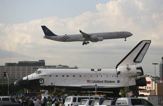 A China Eastern Airlines jet flies near the space shuttle Endeavour in Los Angeles, Friday, Oct. 12, 2012. Endeavour's two-day, 12-mile (19 kilometer) road trip to the California Science Center where it will be put on display kicked off around midnight Friday. Rolled on a 160-wheeled carrier, it left from a hangar at the Los Angeles International Airport, passing diamond-shaped "Shuttle Xing" signs, and reached city streets about two hours later.