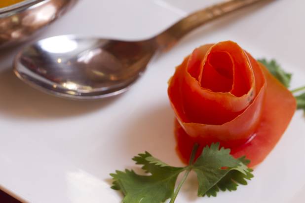 A tomato skin shaped like a flower is shown by a bowl of Chicken Madras curry at Saffron Flavors of India restaurant, 4450 N. Tenaya Way, Sunday, Oct. 14, 2012.  Served with white rice.