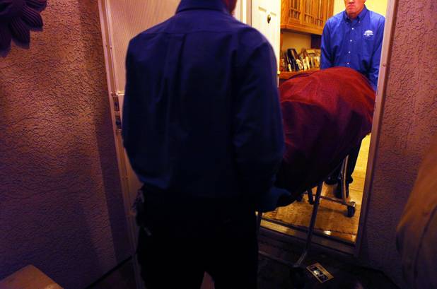Mortuary workers remove a dead body from a home in North Las Vegas.