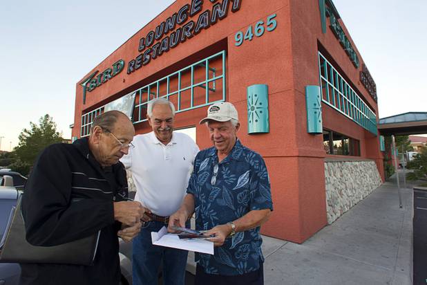 John Bergler, left, and Ron Wright, center, look over Larry Henrichsen's photos of his "new" car -a  1950 Ford coupe - before a Breakfast Club of Automotive Enthusiasts weekly meeting at the T-Bird Restaurant and Lounge, 9465 South Eastern Avenue, Wednesday, Oct. 17, 2012.