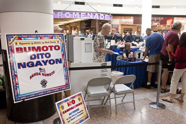 A sign in Tagalog indicating to "Vote Here" next to a sign prohibiting campaigning are posted at the Boulevard Mall voting booths on the first day of early voting, Saturday, Oct. 20, 2012.