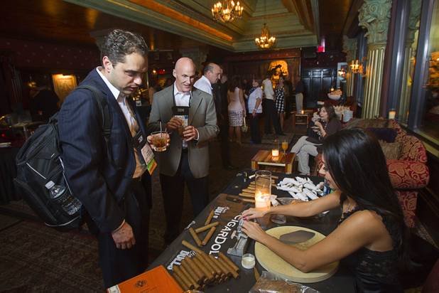 David Mancusi. left, and Mark Yingling watch as Cigar Doll Katrina Kelley rolls cigars during a private party in the Foundation Room at the Mandalay Bay Sunday, Oct. 21, 2012. Cigar Dolls is a company that provides attractive cigar rollers for corporate events or private parties.