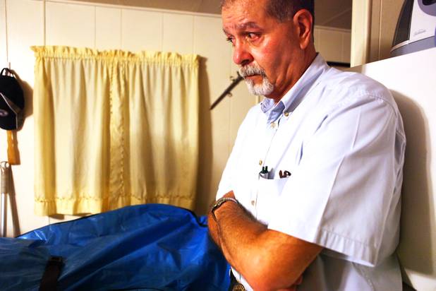 Coroner investigator Rudy Miller looks on as the next of kin says goodbye to the decedent in the blue body bag at a death scene in Las Vegas.