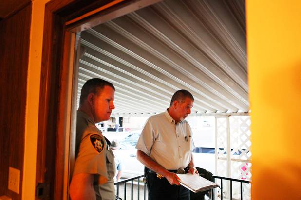 Coroner investigator Rudy Miller, right, with Metro Officer Kerry Ruesch, left, speak to the family of a decedent at the scene in Las Vegas.