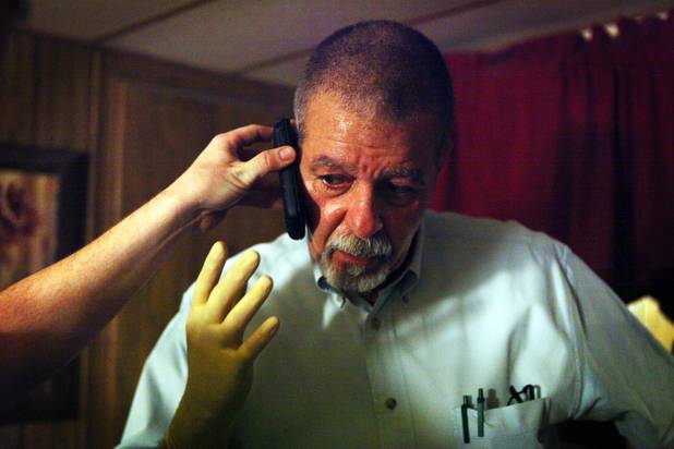 Coroner investigator Rudy Miller takes a phone call while investigating a death scene in Las Vegas.