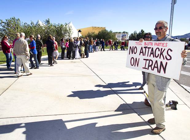 Jim Haber of the Nevada Desert Experience holds a sign urging restraint on Iran policy as Romney supporters wait in line for the Mitt Romney-Paul Ryan campaign rally at the Henderson Pavilion Tuesday, Oct. 23, 2012.