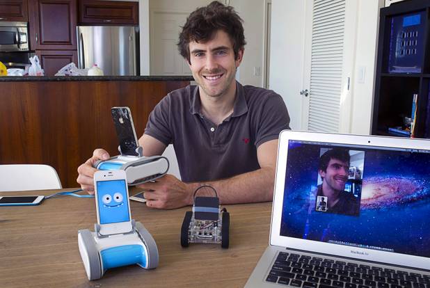 Keller Rinaudo, one of the three Romotive founders, poses  with the new Romo smartphone robot at the Romotive offices in downtown Las Vegas Wednesday, Oct. 24, 2012.  The original model is at center. The new Romo can be controlled over the Internet. Rinaudo's face, captured by the Romo in his hands, is shown on the computer screen at right. The new Romo with enhanced features can be ordered on kickstarter.com and is featured in the Neiman Marcus Holiday catalog.