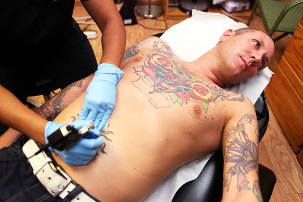 Technician Magdelyn Vasquez-Castro removes a tattoo from the stomach of ...