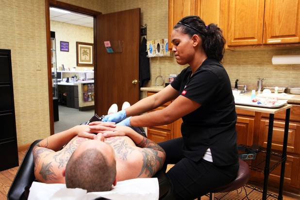 Technician Magdelyn Vasquez-Castro removes a tattoo from the stomach of ...