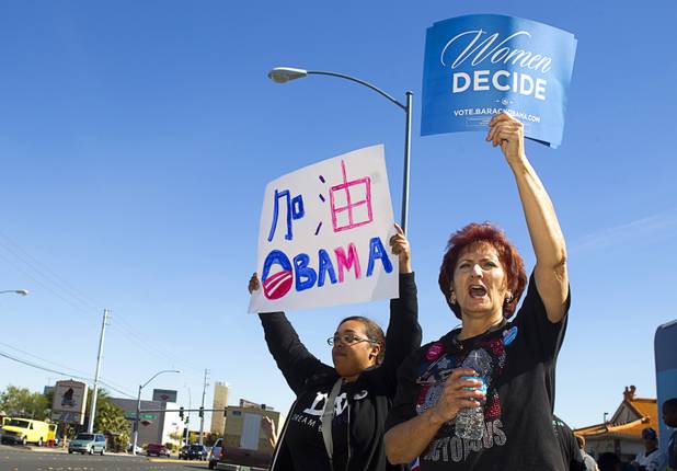 Laura Martin, left, and Sandy Eddy hold up signs before an Asian American and Pacific Islander early voting rally for President Obama at the Chinatown Mall on Saturday, Oct. 27, 2012. The sign with Chinese characters at left reads "All the way!" Obama.