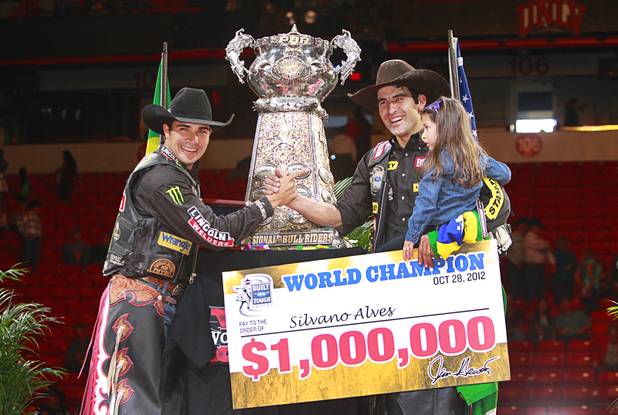 Brazilian bull riders Robson Palmero, left, and Silvano Alves pose for a photo during the Built Ford Tough Series Professional Bull Riders (PBR) World Finals at the Thomas & Mack Center Sunday, Oct. 28, 2012. Palmero was the event champion and Alves won the series championship. Alves holds his 3-year-old daughter Hanyelle.