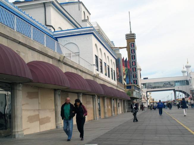 Pedestrians walk past the boarded-up windows of Resorts Casino Hotel in Atlantic City N.J. on Saturday Oct. 27, 2012. 