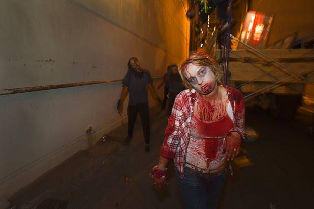 A zombie follows a group going through the Haunted Alley during Halloween in downtown Las Vegas Wednesday, October 31, 2012.