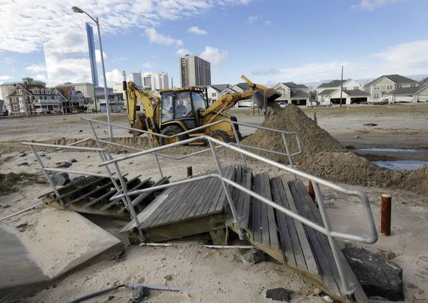 A worker uses a backhoe to clear sand and debris that was carried onshore by surge from superstorm Sandy in Atlantic City, N.J., Wednesday, Oct. 31, 2012. Sandy, the storm that made landfall Monday, caused multiple fatalities, halted mass transit and cut power to more than 6 million homes and businesses. (AP Photo/Patrick Semansky)