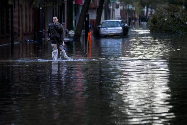 David Bagatelle, of Hoboken, N.J., walks from his residence on Park Avenue through high water in Hoboken, N.J., Wednesday, Oct. 31, 2012, in the wake of superstorm Sandy. Bagatelle's home is surrounded by water, but dry, where his wife and seven day old baby are staying. (AP Photo/Craig Ruttle)