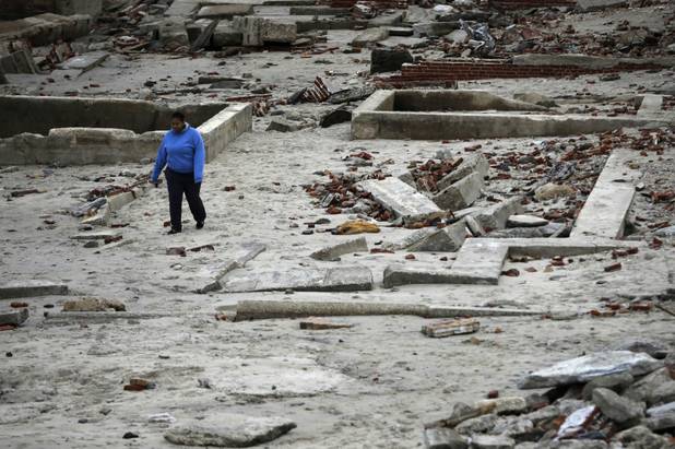 A woman walks past the remains of buildings in the wake from superstorm Sandy, Wednesday, Oct. 31, 2012, in Atlantic City, N.J. Sandy was being blamed for at least six deaths across the state plus power outages that at their peak Monday affected 2.7 million residential and commercial customers. (AP Photo/Matt Slocum)