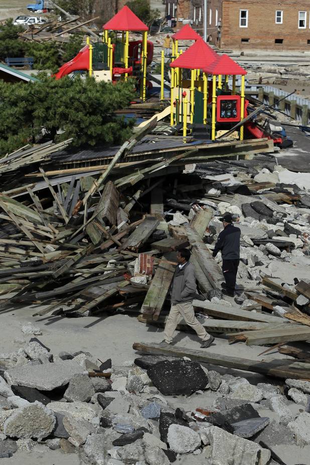 Men walk through debris from a damaged section of the boardwalk in the wake from superstorm Sandy, Wednesday, Oct. 31, 2012, in Atlantic City, N.J.  Sandy was being blamed for at least six deaths across the state plus power outages that at their peak Monday affected 2.7 million residential and commercial customers. (AP Photo/Matt Slocum)