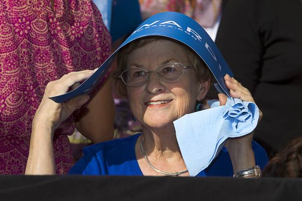 A woman uses a campaign sign to keep the sun off her head during President Barack Obama's campaign rally at the Cheyenne Sports Complex near the College of Southern Nevada in North Las Vegas Thursday, Nov. 1, 2012.
