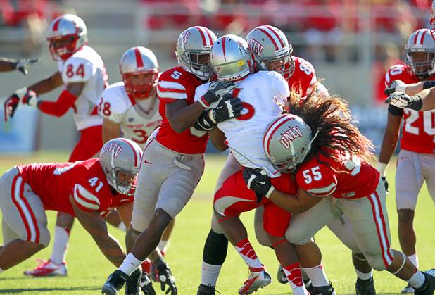 UNLV defenders Dre Crawford, left, Jordan Sparkman, center, and John Lotulelei put a stop to a run by New Mexico's Jhurell Pressley during the first half of their game at Sam Boyd Stadium Saturday, Nov. 3, 2012.