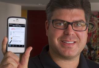 Tommy Bell, founder of SalonShare.com, holds a iPhone displaying his company's website at his office Monday, Nov. 5, 2012. Bell says says it can be quite hard for companies to get startup financing, largely because there is a small number of local tech investors.