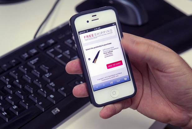 Tommy Bell, founder of SalonShare.com, holds a iPhone displaying a product on the SalonShare website at his office Monday, Nov. 5, 2012. Bell says says it can be quite hard for companies to get startup financing, largely because there is a small number of local tech investors.