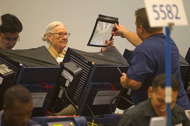 Team leader Josh Clevenger gives a magnifying sheet to voter Lillian Steele on Election Day at the Cambridge Recreation Center Tuesday, Nov. 6, 2012. Steele was having trouble reading the screen, she said.