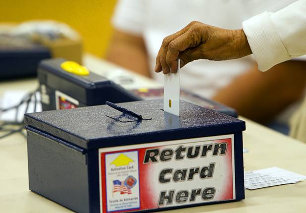 An election worker deposits a voting card into a box on election day at the Fremont Middle School gym Tuesday, November 6, 2012.