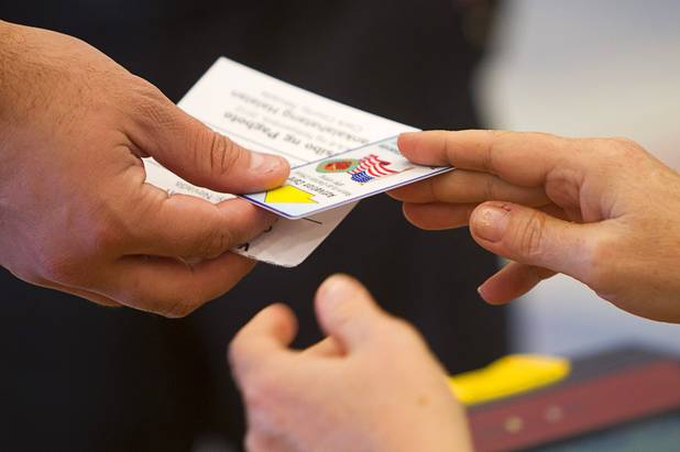 An election worker hands a voting card to a voter on election day at Paradise Elementary School Tuesday, November 6, 2012.