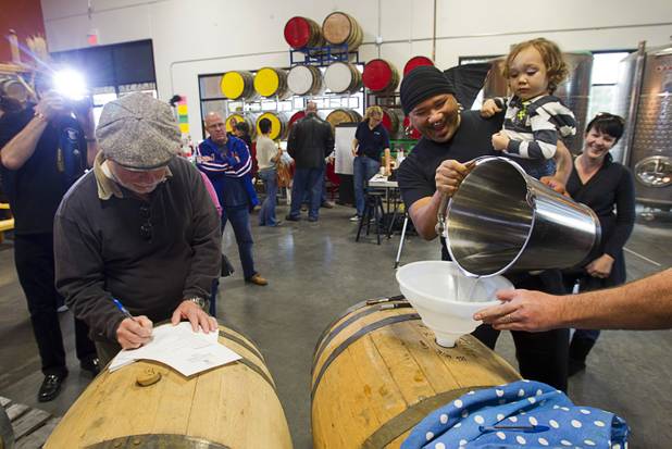 David Kekone, right, helps fill a barrel with single malt whiskey as his son Dante Xavier Kekone, 2, looks on during the Historic First Edition Day at the Las Vegas Distillery in Henderson Saturday, November 17, 2012. The event marks the first bottling of several new spirits and the grand opening of the Booze Brothers Beverage distribution company and the Half Full Artisan Shop at the Distillery, a retail store. The spirits include Nevada vodka, whiskey, gin, rum and moonshine.